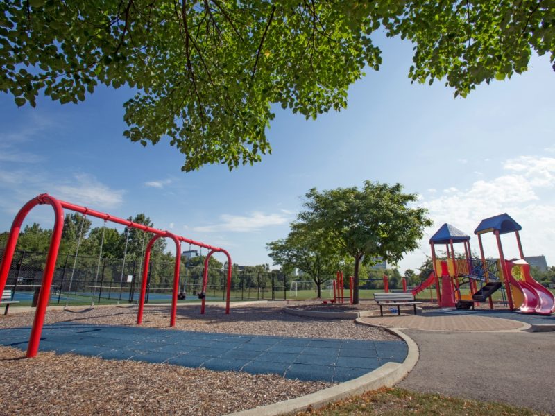 This image shows a spacious playground area with safety equipment featuring the slides and swings.